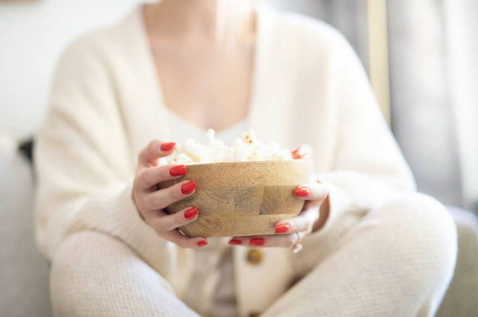Woman holding a mango wood bowl filled with popcorn | Shop Hygge Box