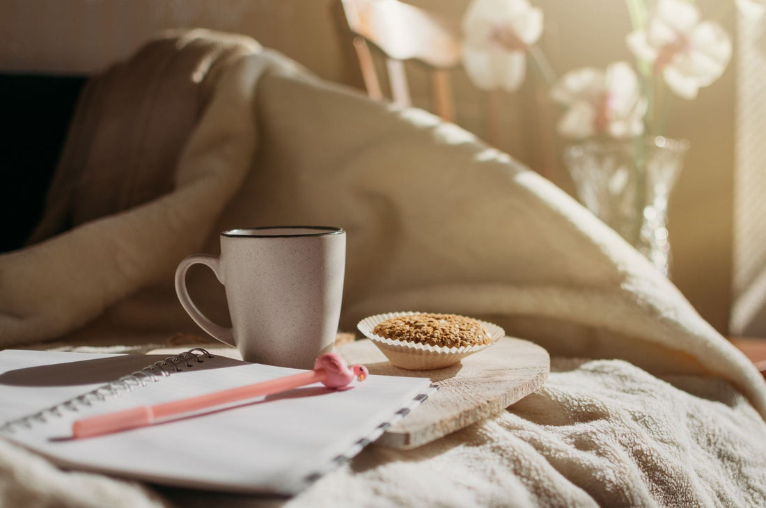 A warm mug, open journal, and soft blanket in golden morning light, the perfect hygge staycation setup at home