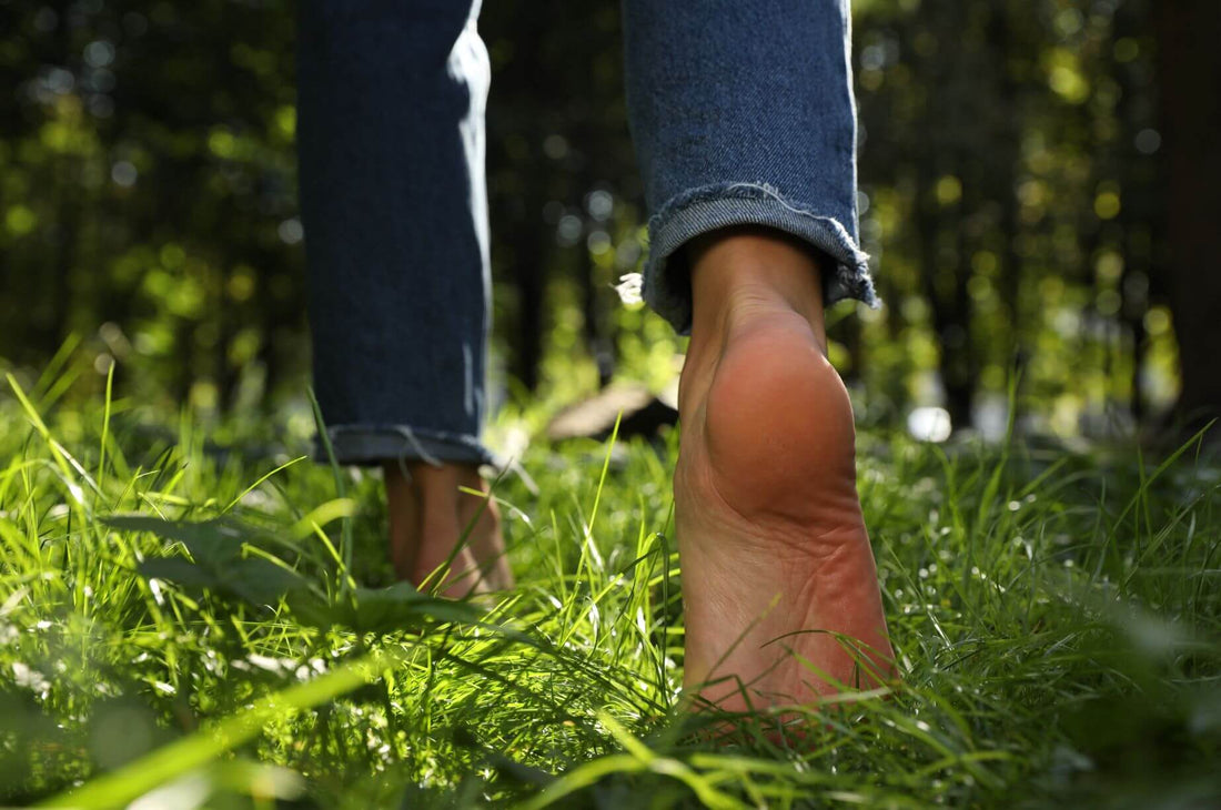 Barefoot person walking through sunlit grass, embracing gentle outdoor movement and everyday well-being.