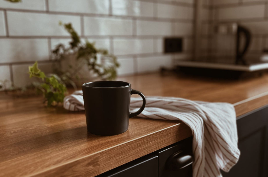 a black mug sitting on a kitchen counter with a dish towel nearby