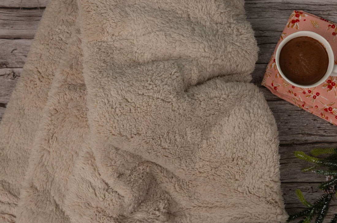 Cozy beige blanket with a cup of hot chocolate.