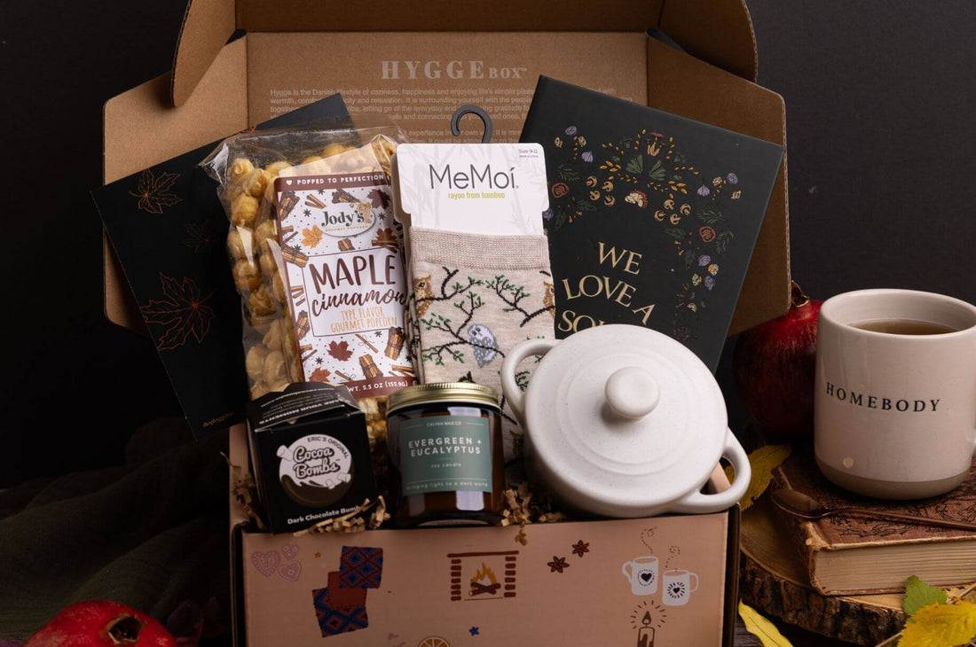 October Hygge Box with maple cinnamon popcorn, owl bamboo socks, soup cookbook, white mini cocotte, evergreen eucalyptus candle, and cocoa bomb.