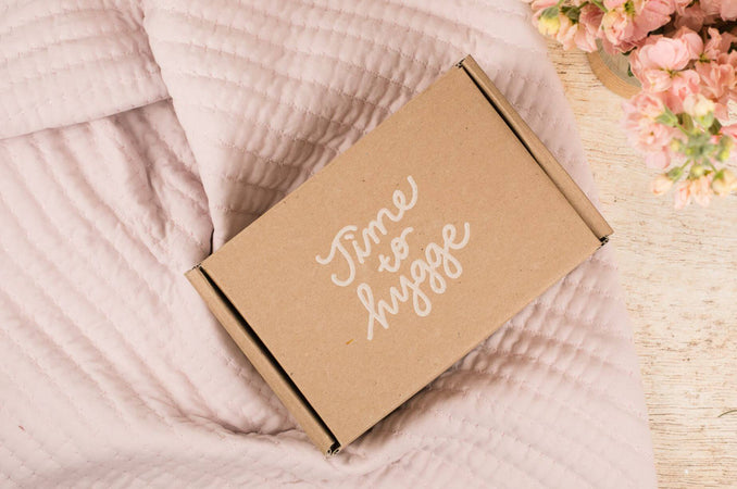 Time to Hygge Box on Soft Pink Blanket with Flowers in Background