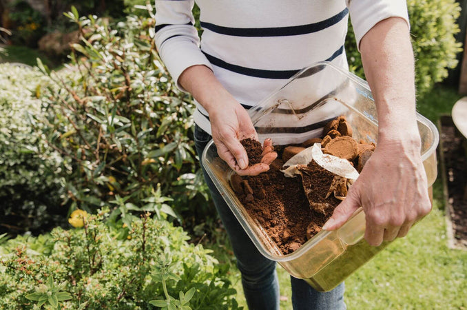 Woman holding a container filled with coffee grounds