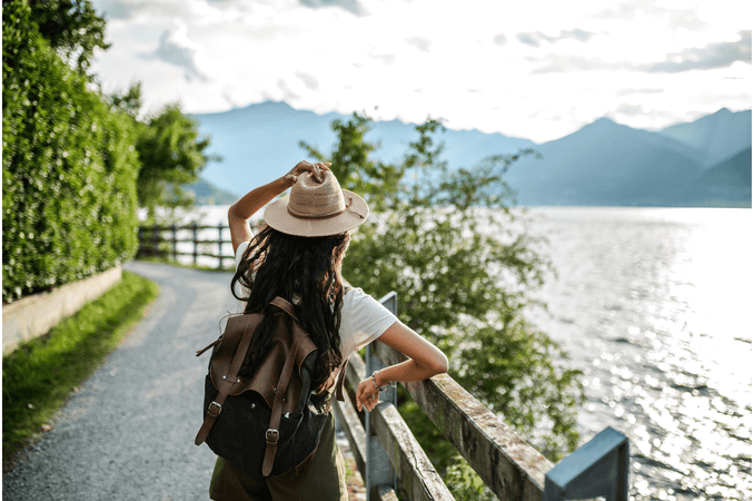 Making Travel Hygge - Young woman starring out into water and mountains on a sunny day