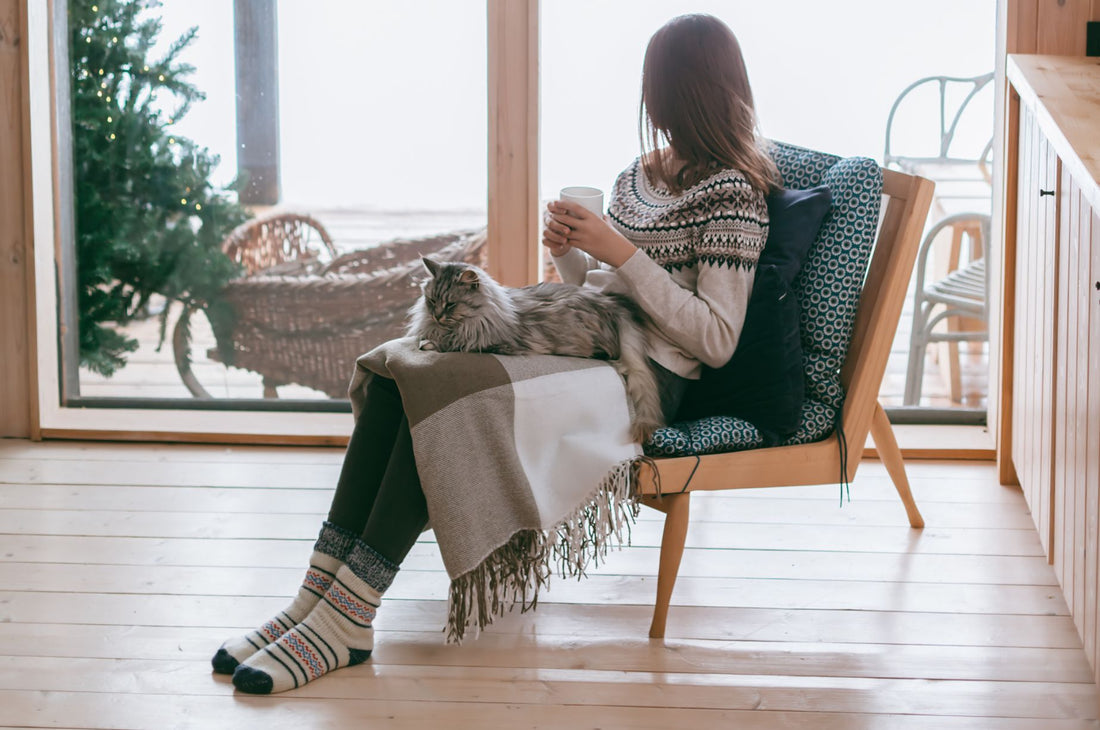 Woman sitting in chair with her cat holding a warm beverage