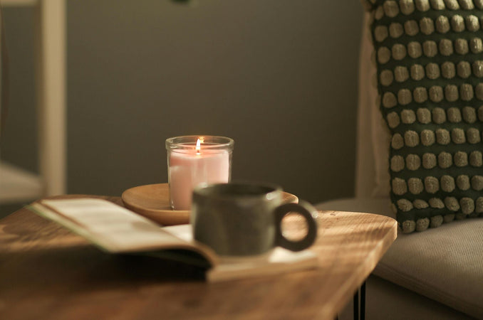 Blog post featuring 30 quick and easy self-care ideas for busy people. A side table with a lit candle, mug and book.