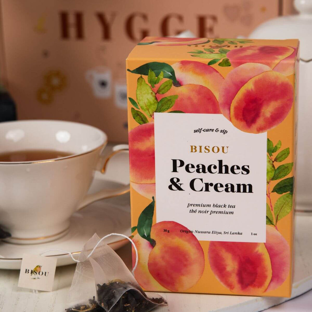 Bisou Peaches & Cream tea packaging with a cup of tea in the background