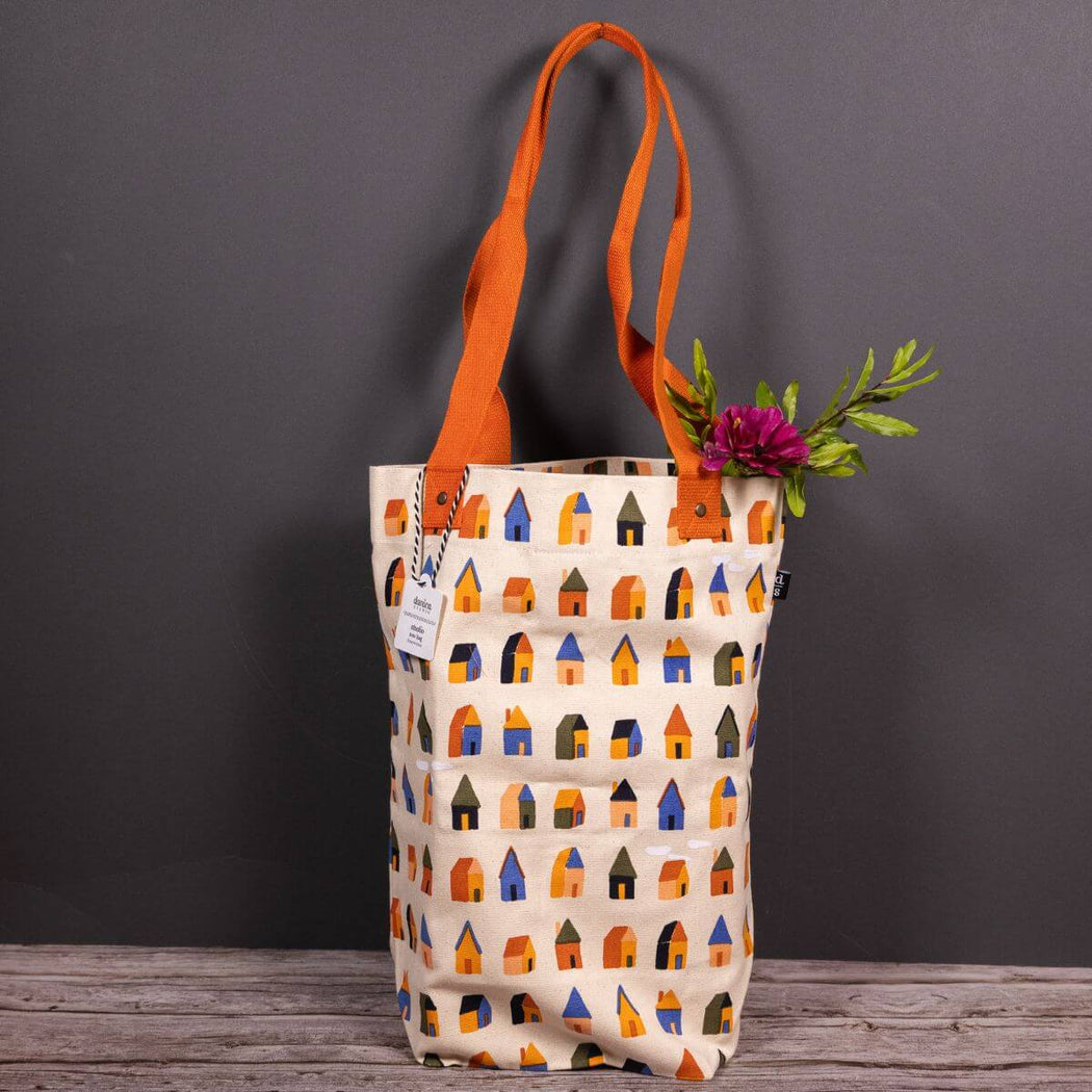 Tote bag with house pattern and orange handle on a gray background