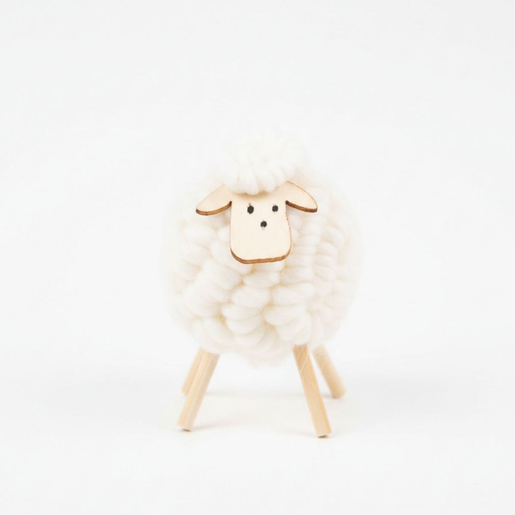 White sheep figurine with wooden legs on a white background