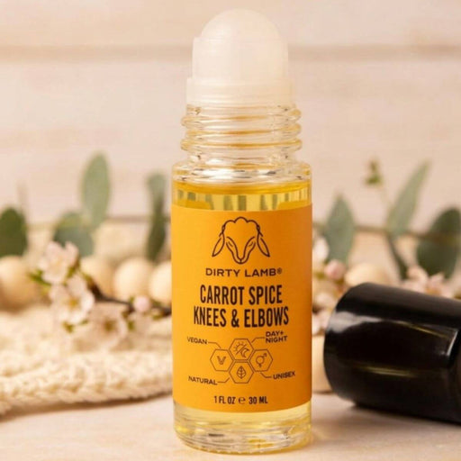 Bottle of 'Carrot Spice Knees & Elbows' product by Dirty Lamb on a blurred background with flowers and a black bag.