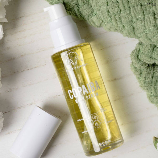 Bottle of Copaiba body serum on a light surface with a green towel in the background