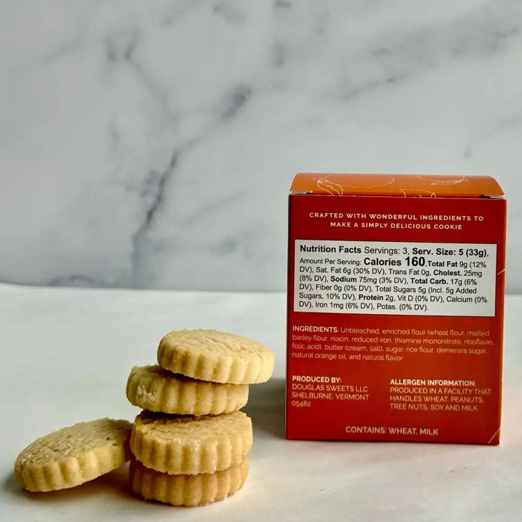 Back of Douglas Sweets Orange Blossom Cookies box showing nutrition facts, ingredients, and stacked buttery shortbread cookies on marble surface