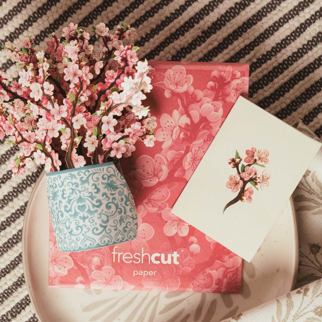 Floral arrangement with a 'freshcut paper' box on a textured surface