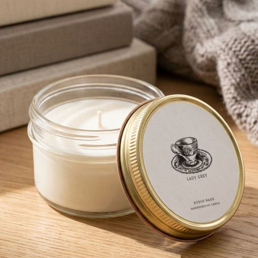 Candle in a glass jar with a gold lid on a wooden surface