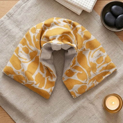 Yellow patterned neck wrap on a textured surface with a candle and stones in the background