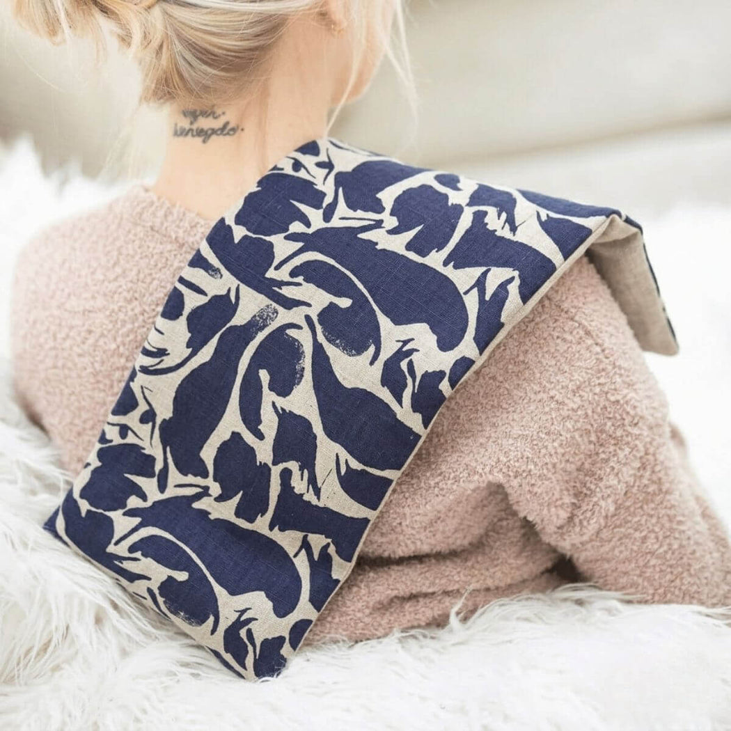 Woman wearing navy linen wheat wrap heat pack on shoulders for neck and shoulder heat therapy.