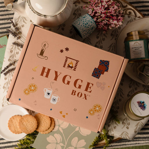 Pink 'Hygge Box' on a table with tea and cookies