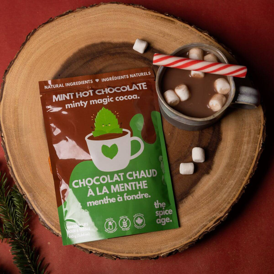 Hot chocolate package with a mug of hot chocolate and marshmallows on a wooden surface.