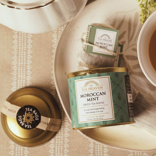 Tea Heaven Moroccan Mint green tea blend packaging on a table with a teacup and saucer.