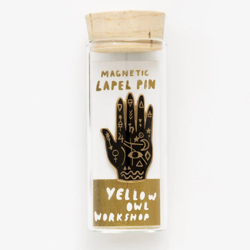 Magnetic lapel pin packaging with hand design and 'Yellow Owl Workshop' branding.