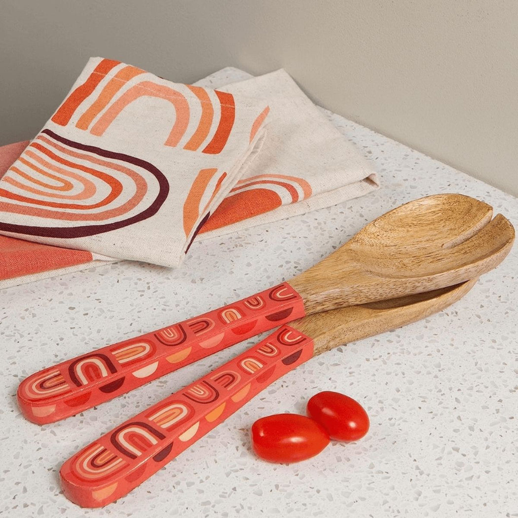 Two wooden spoons with coral color handles featuring a rainbows pattern.