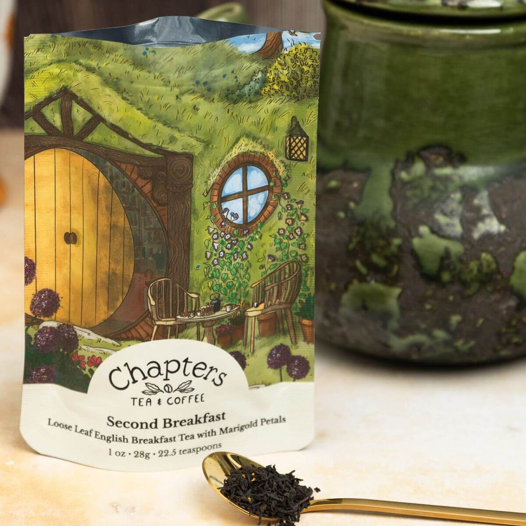 Tea package labeled 'Chapters Tea & Coffee' with a green ceramic mug and spoon on a wooden surface.