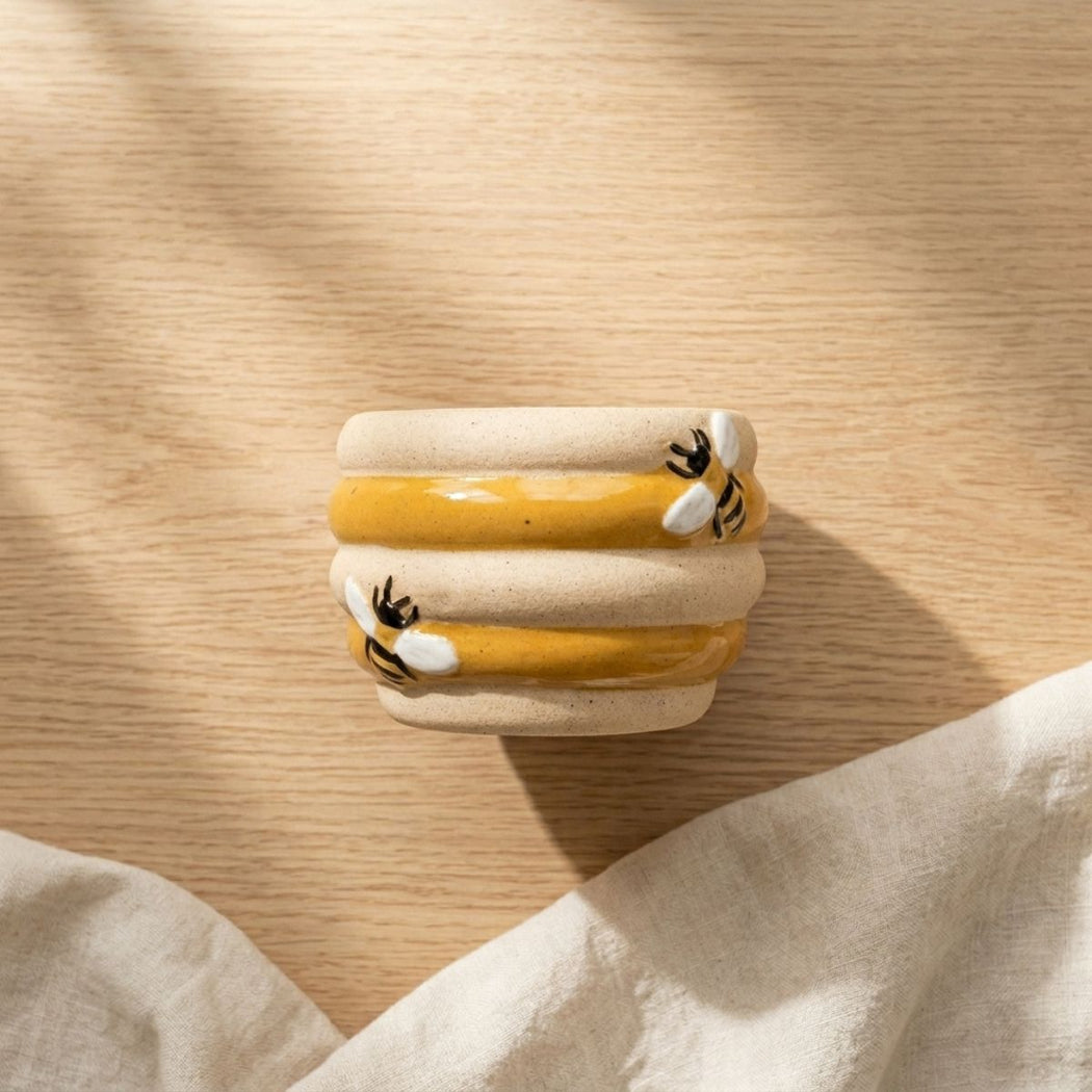Small ceramic planter pot with yellow stripes on a wooden surface