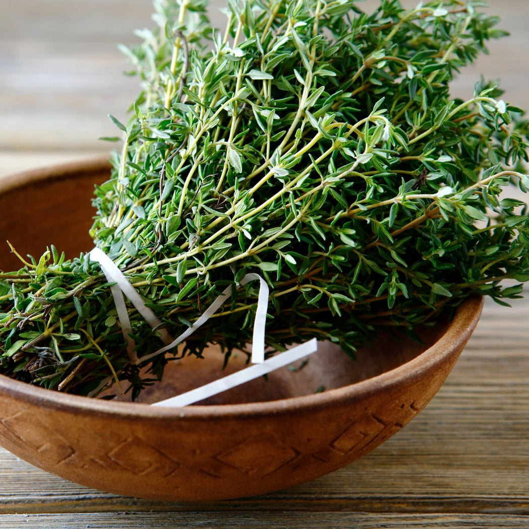 Bouquet of fresh thyme in a wooden bowl on a wooden surface