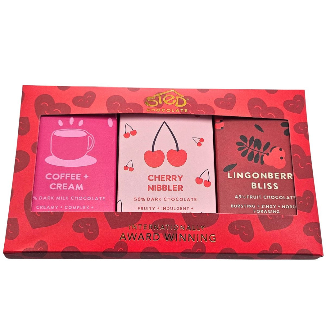 Red chocolate box with three different chocolate bars inside, each labeled with flavor and branding.
