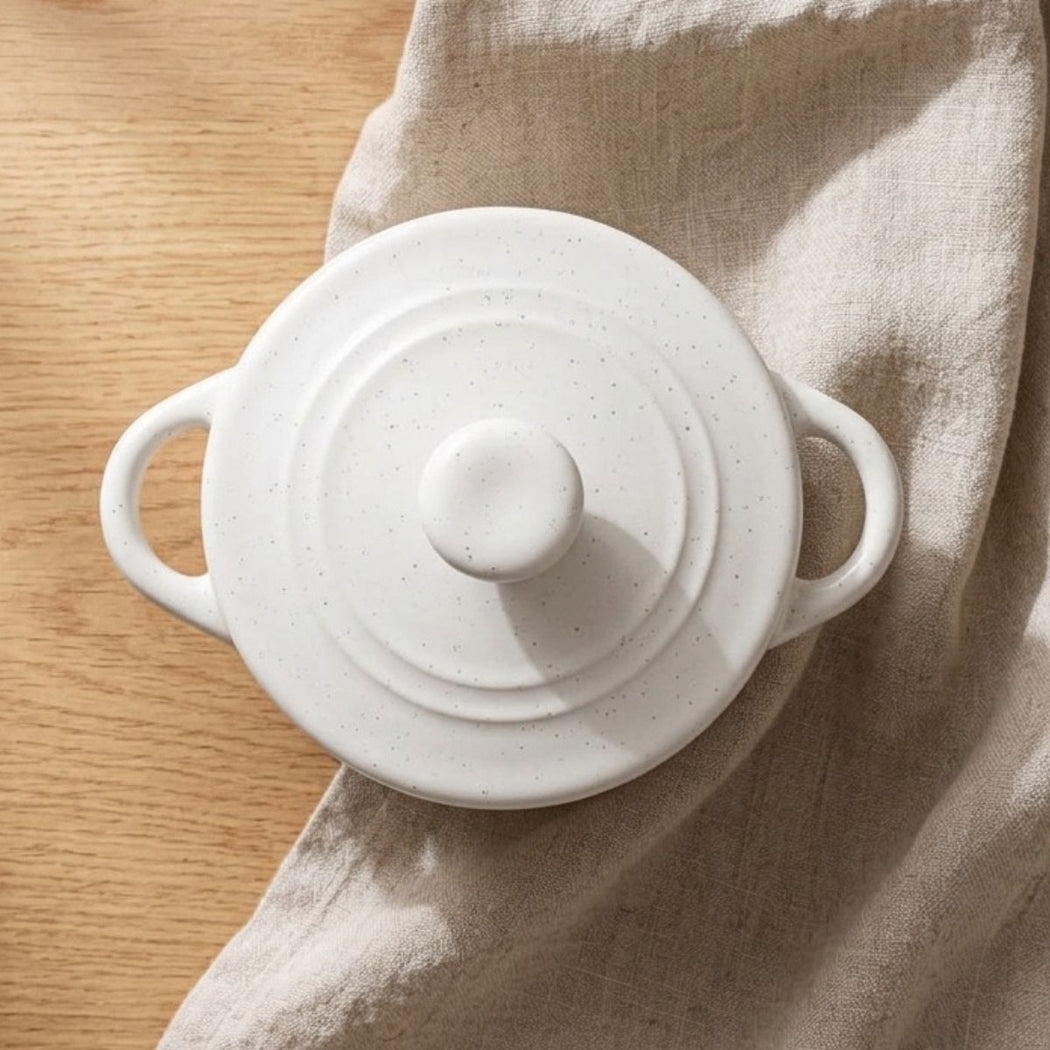 White ceramic pot with lid on a beige cloth