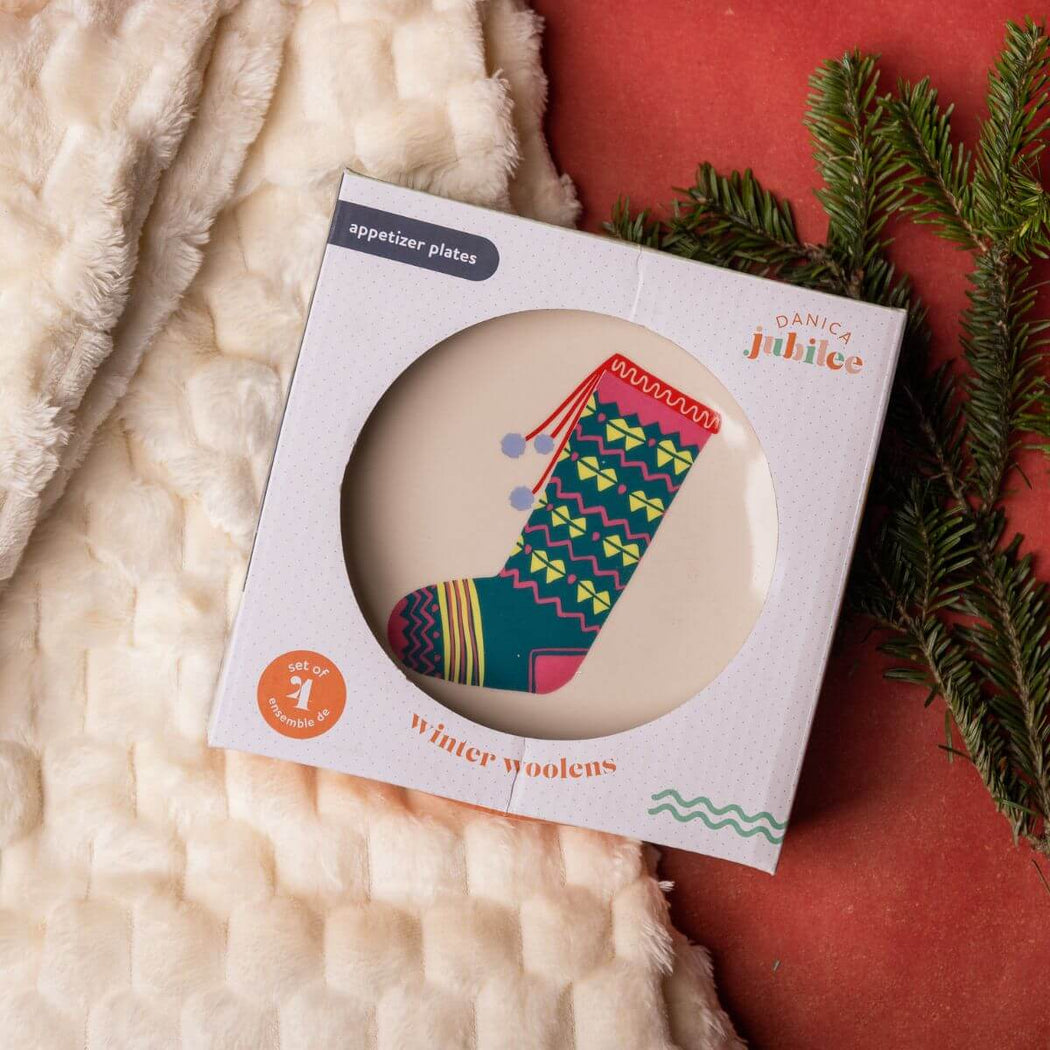 Packaged appetizer plates with a stocking image on a textured surface with greenery