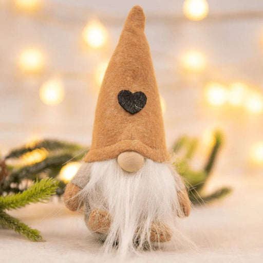 Gnome figurine with a heart on its hat against a blurred background of lights and greenery