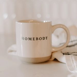 Beige mug with 'HOMEBODY' text on a light background