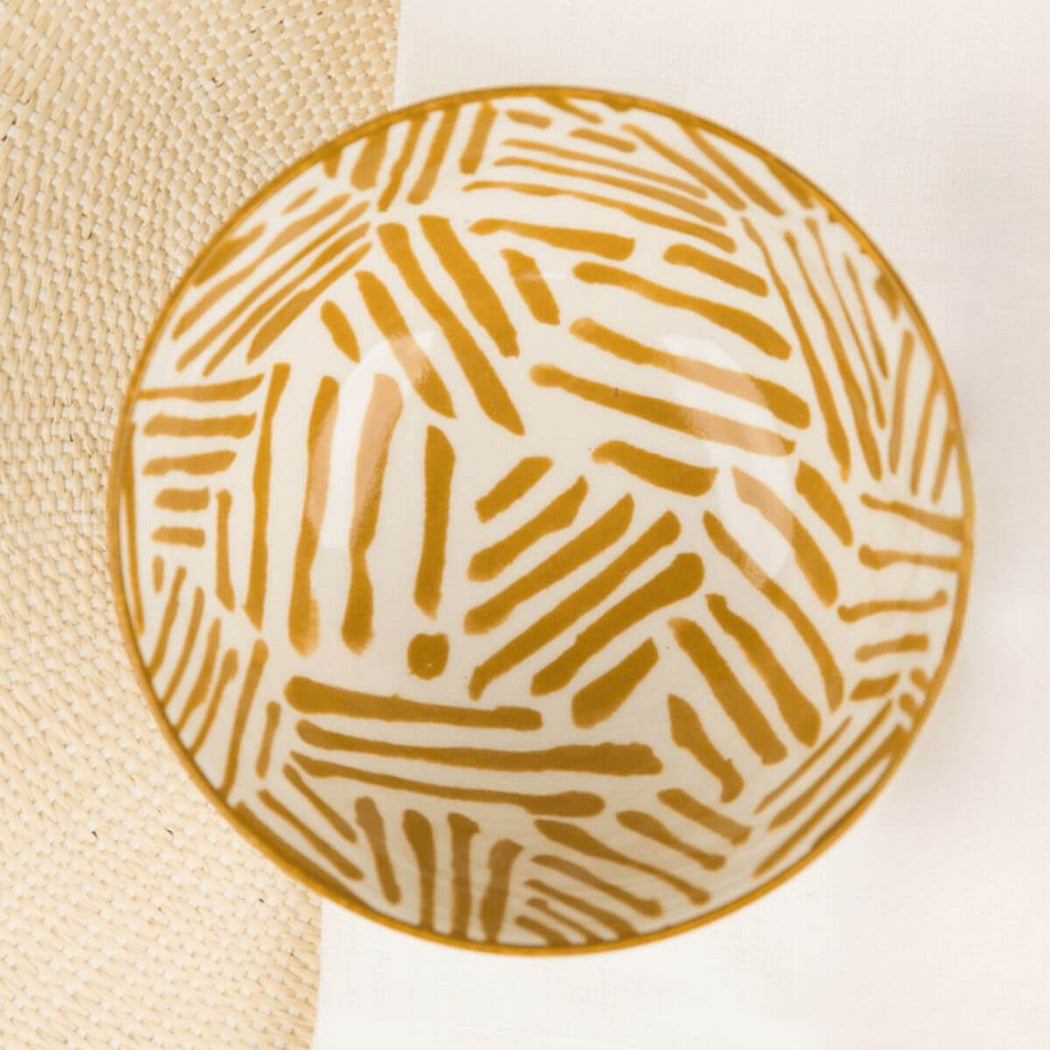 Round ceramic plate with ochre geometric pattern on a beige and white background
