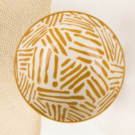 Round ceramic plate with ochre geometric pattern on a beige and white background